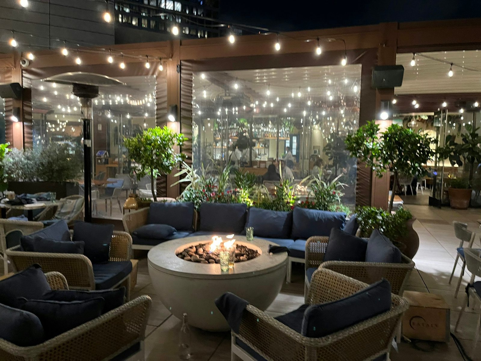 Rooftop restaurant design with lounge seating, fire pit and string lights
